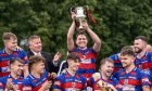 Kingussie captain Calum Grant lifts the MacAulay Cup.  Image: Neil Paterson.