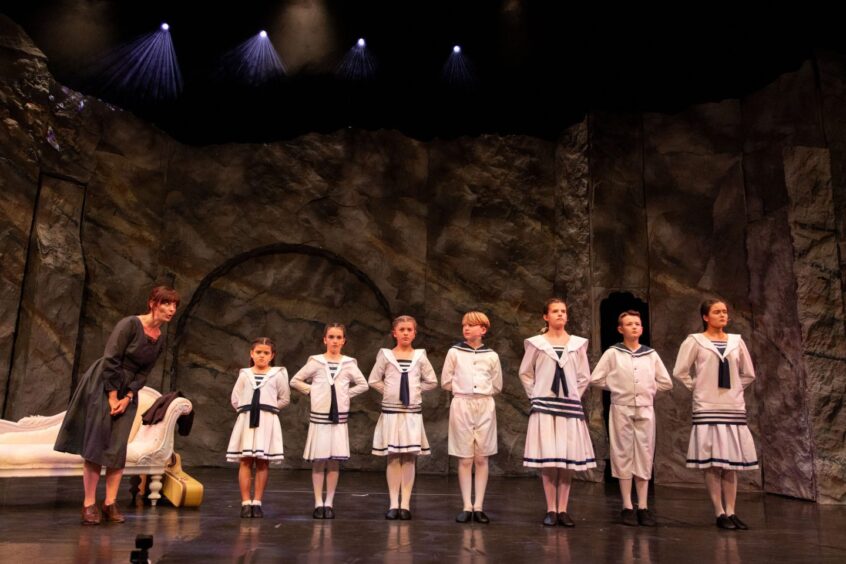 Maria meets the Von Trapp children for the first time. They are lined up in their sailor suits.