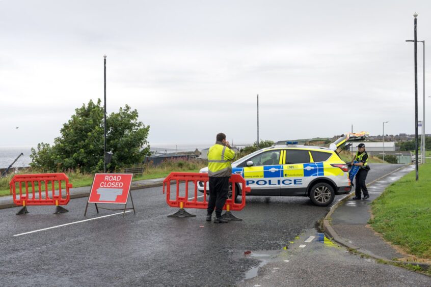 Police officers, car and road closed sign on Buckie road