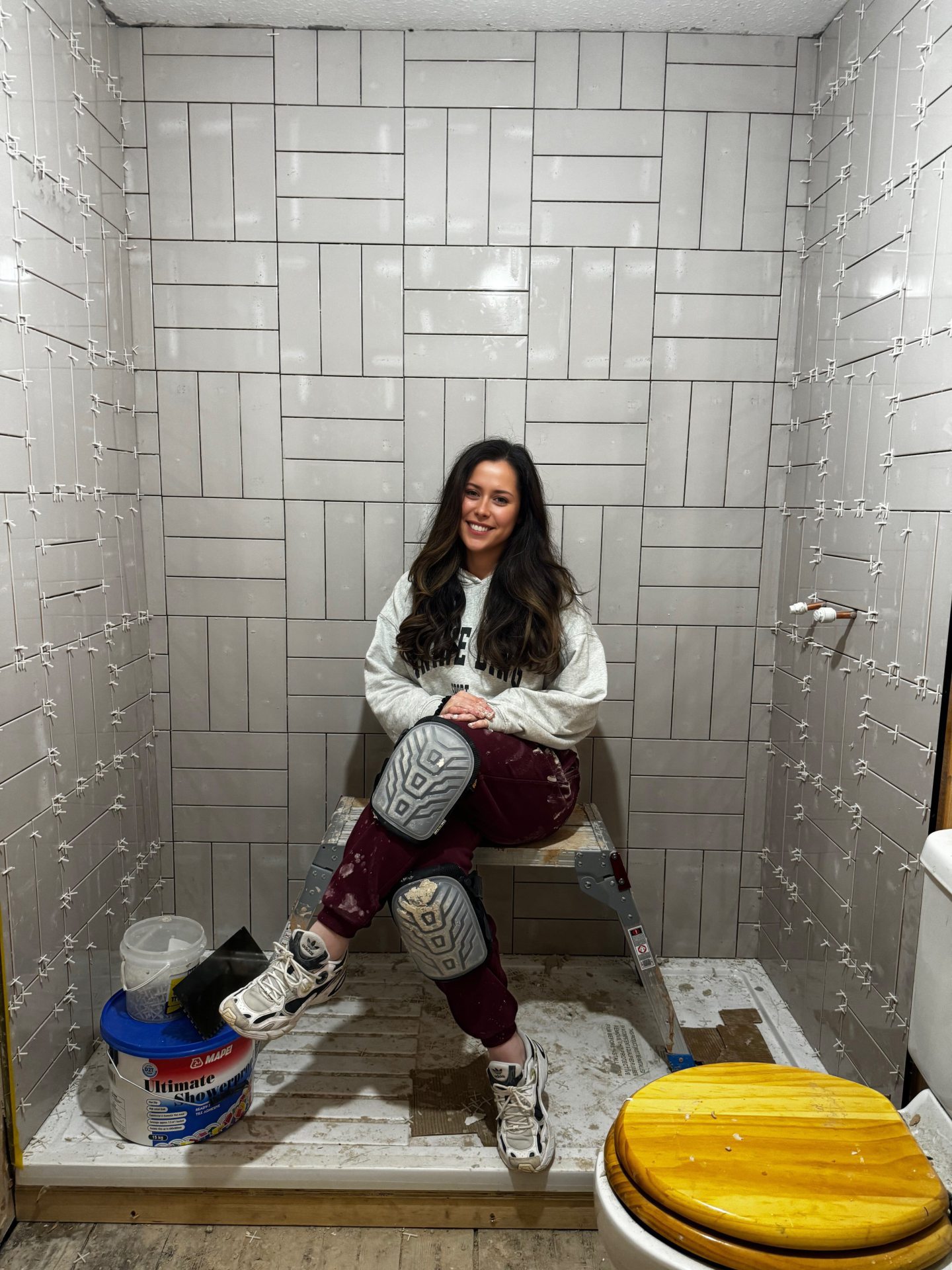 Emma, sitting where the shower would later be, halfway through renovating the bathroom