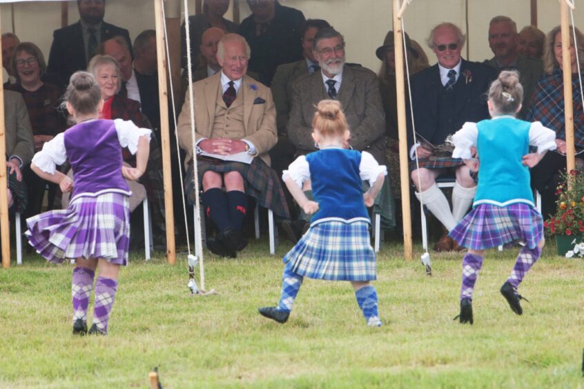 Highland dancers in coloured tartan outfits perform for King Charles.