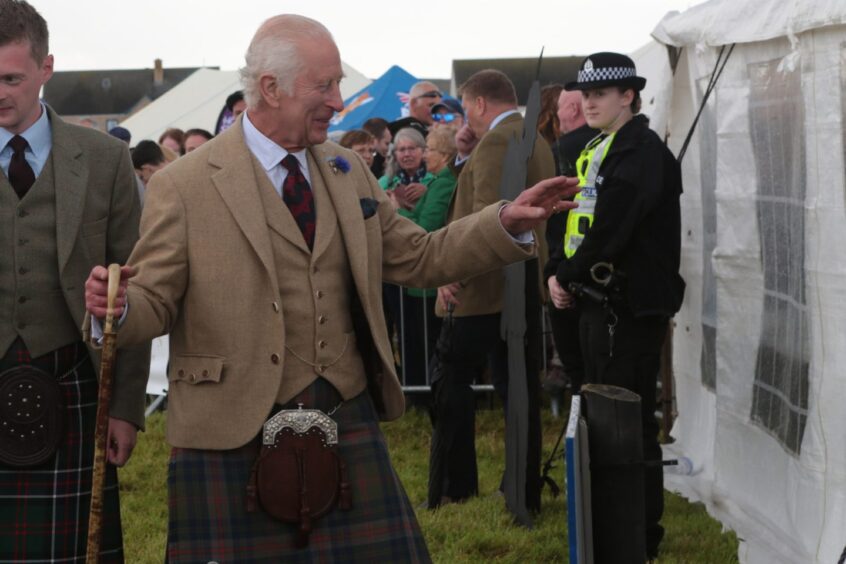 King Charles smiles and waves to fans at the games.