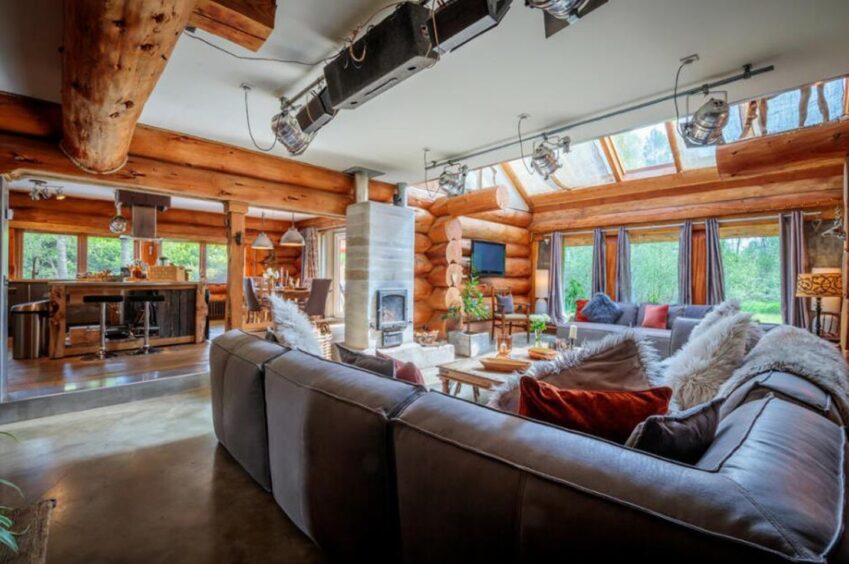 Lounge area with log fire, grey settee and large windows.