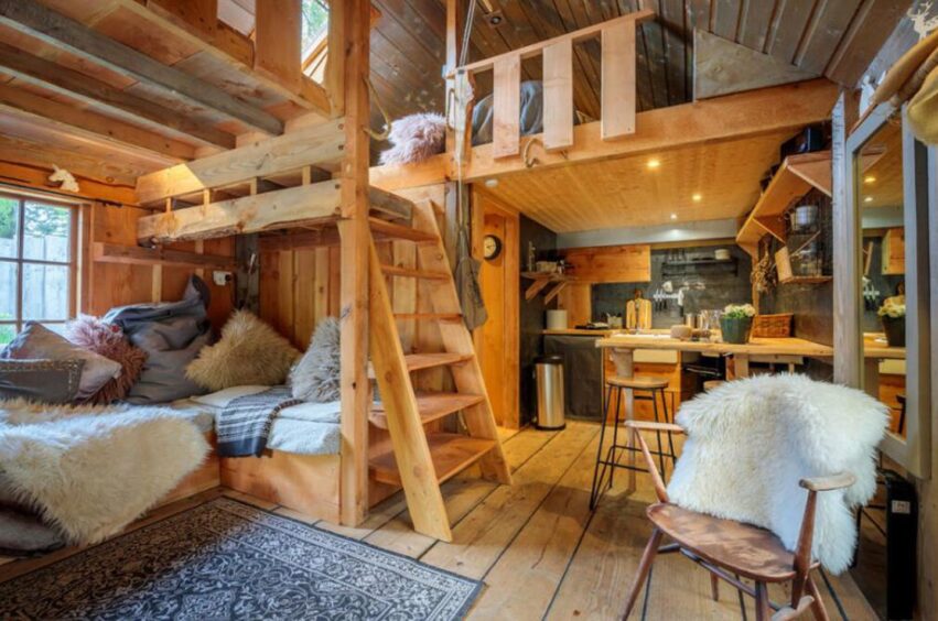 Attic space complete with wooden ladder, loft space, kitchen and small lounge area.