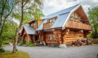 The three-storey wooden house amidst green trees.