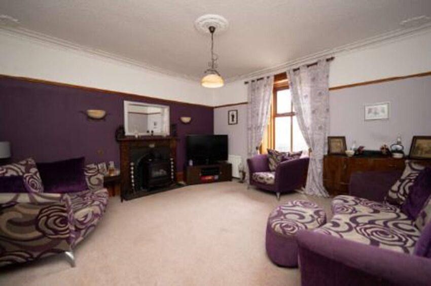 Sitting room with Log-burning stove and purple furniture.