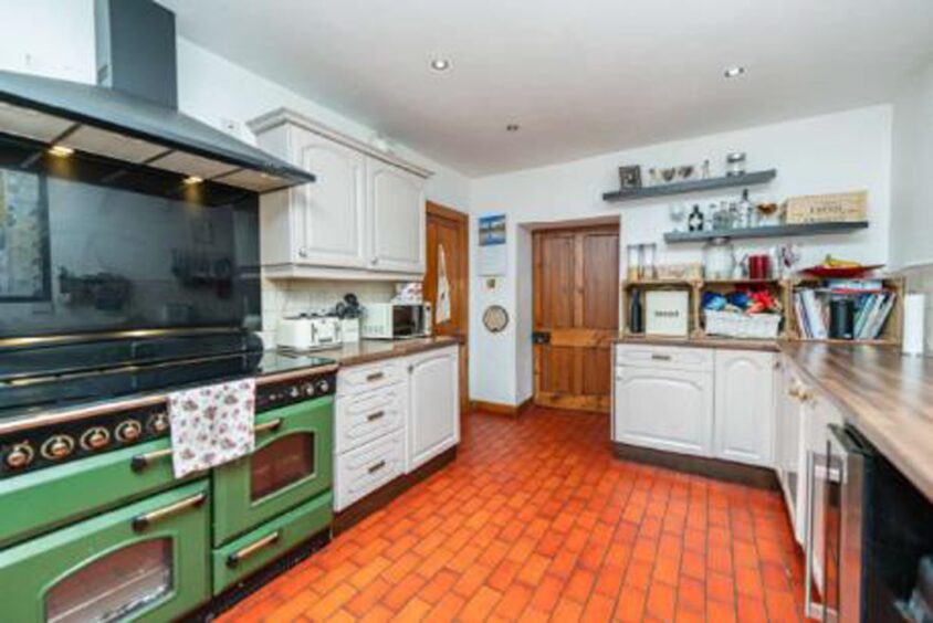 Kitchen with red/orange floor tiles.