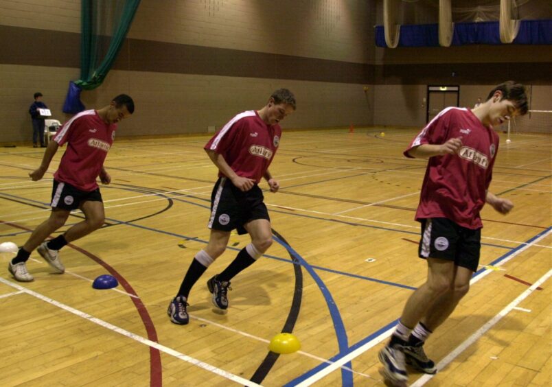 Turn of the century Aberdeen stars Chris Clark (centre) and Derek Young (right) steal a step on Rachid Belabed (left) during a training session at the Beach Leisure Centre. Image: DC Thomson