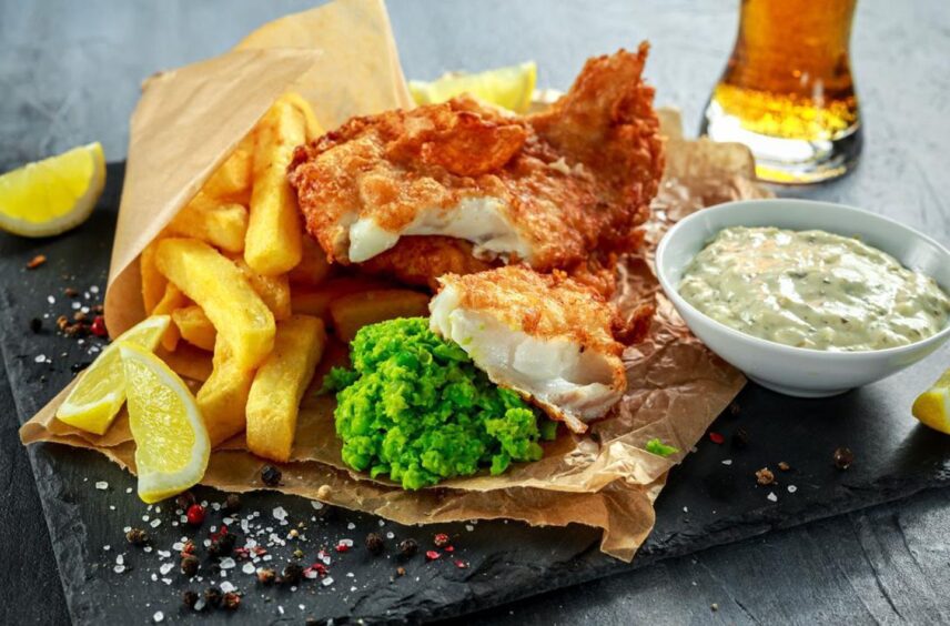 fish and chips on a wooden serving board. 