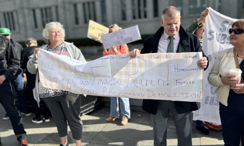 Affected Torry locals outside Aberdeen city council office ahead of Raac meeting with sign that reads 'Homeless and financial ruin! If you recommend demolition'.