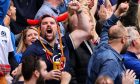 A Scotland rugby fan enjoys a game at Murrayfield while drinking a beer. Image: Shutterstock.