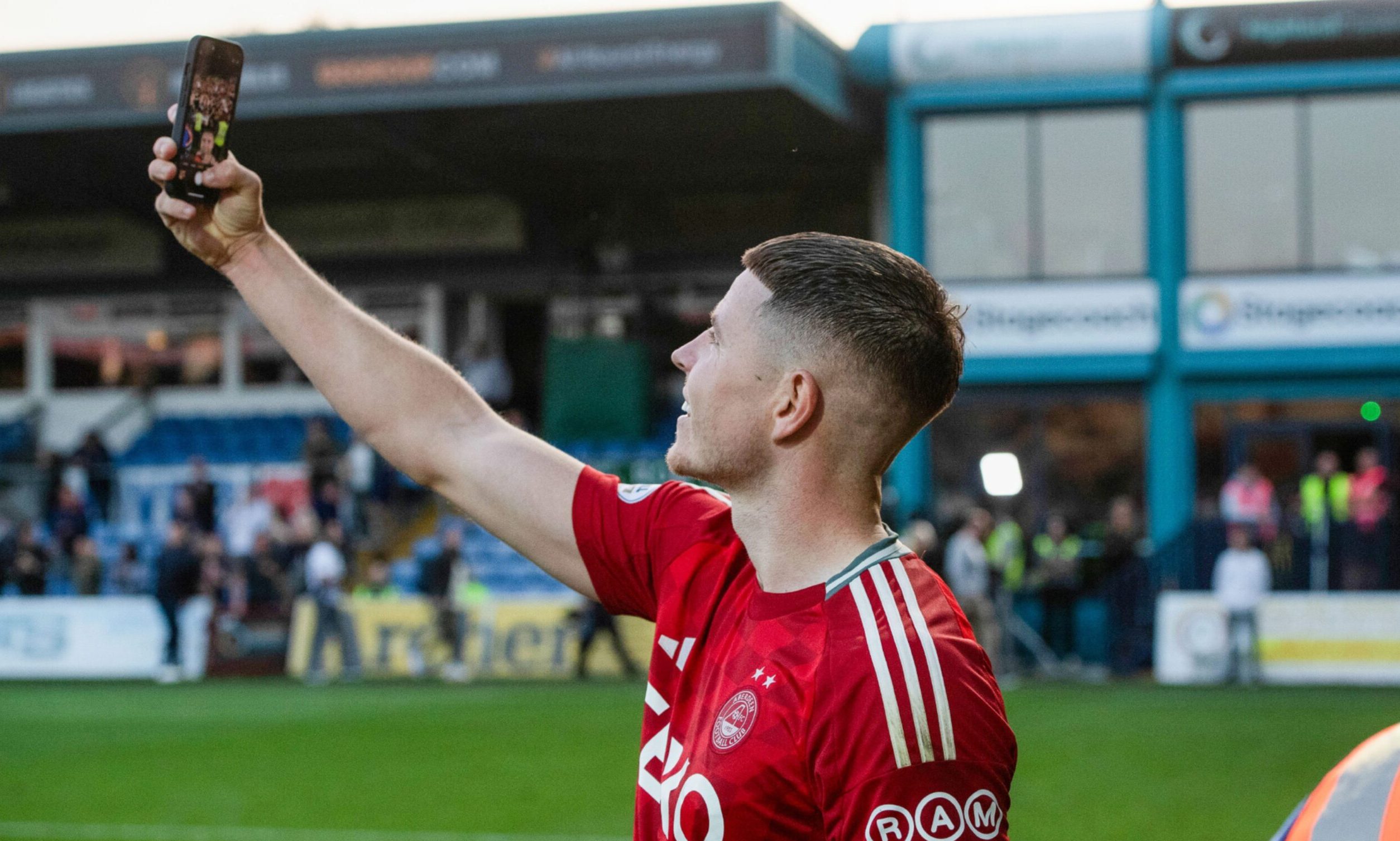 Aberdeen's Kevin Nisbet takes a picture with the fans at full time after the 1-0 win against Ross County. Image; SNS