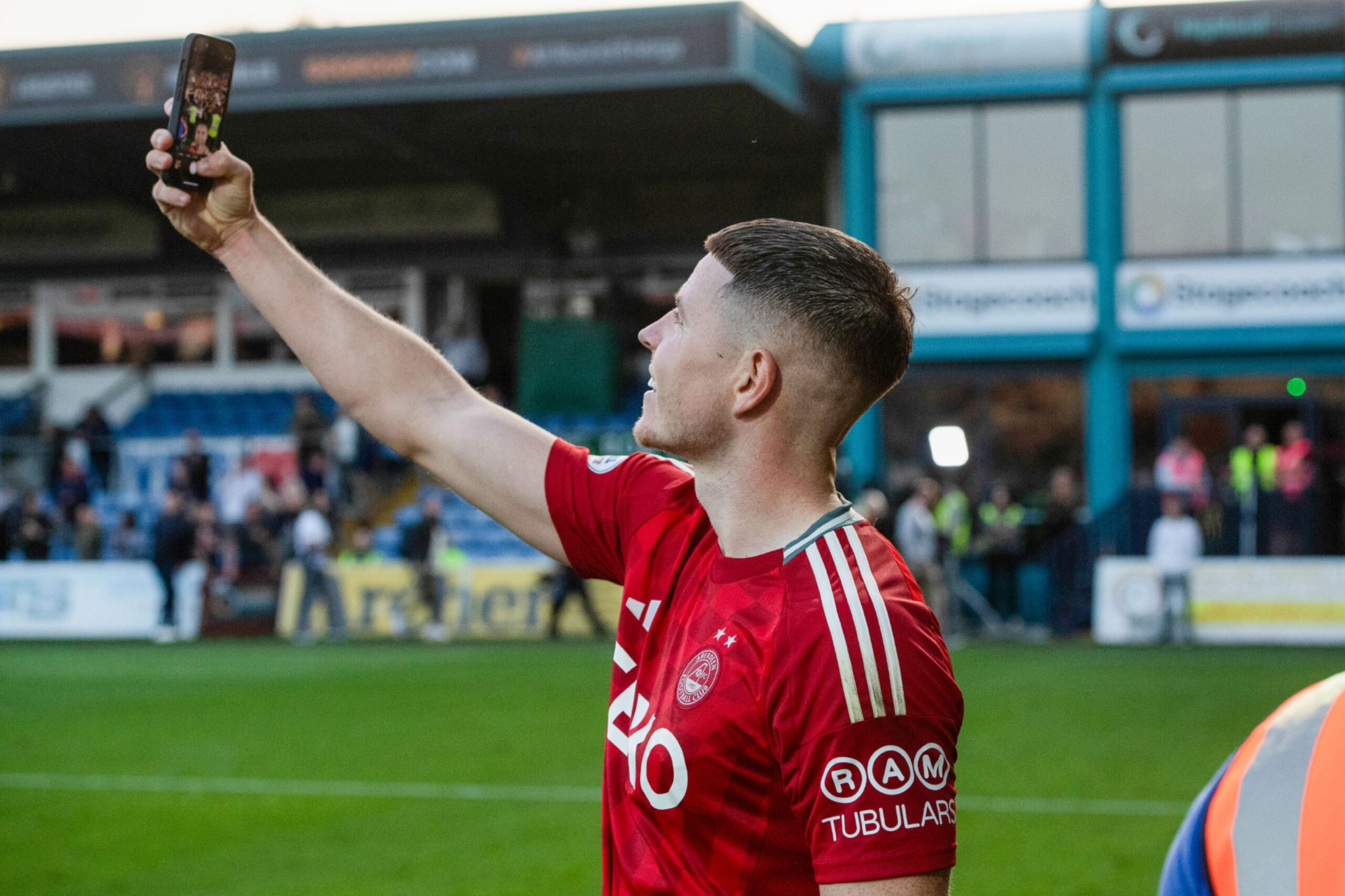  Aberdeen's Kevin Nisbet takes a picture with the fans at full time after the 1-0 win against Ross County. Image; SNS 