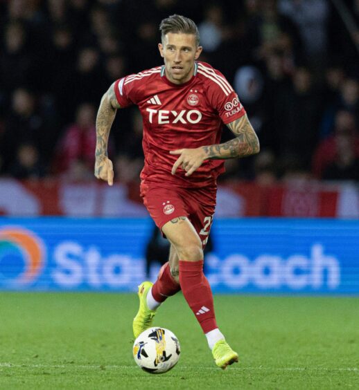 Angust MacDonald running with the ball for Aberdeen FC.