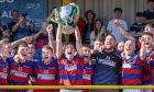 The Kingussie team celebrate as captain Calum Grant lifts the Camanachd Cup.  Image: Neil Paterson.