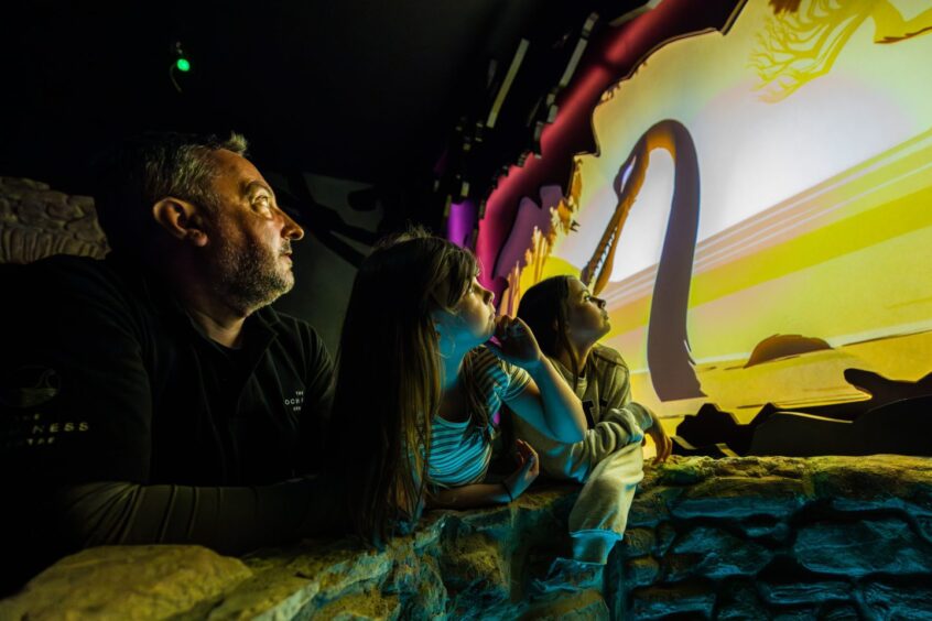 man with two girls watch an exhibit at Loch Ness Centre