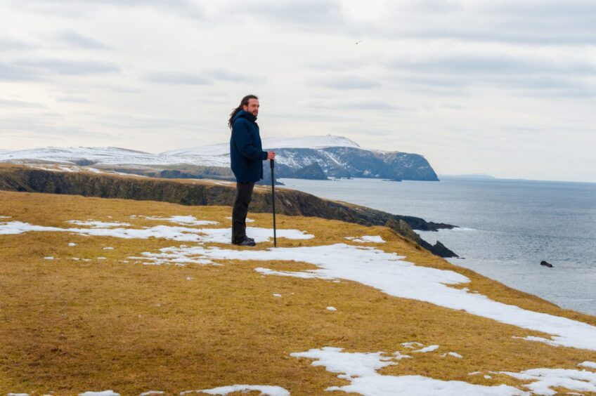 Young handsome man looking out to the sea, St Ninian's, Shetland Islands, Scotland