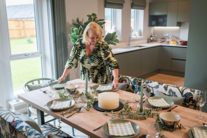 woman arranges table settings in the dining room of a house in Scotia Homes' Dalfaber development