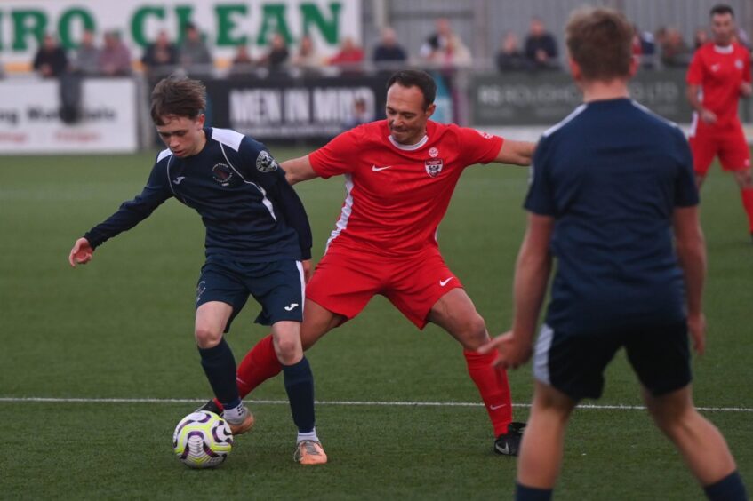 Darren Young, former Dons player, battling the Cove Youth side for the ball.