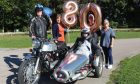 Irene with her family around the motorcycle with 80 birthday balloons in the background.