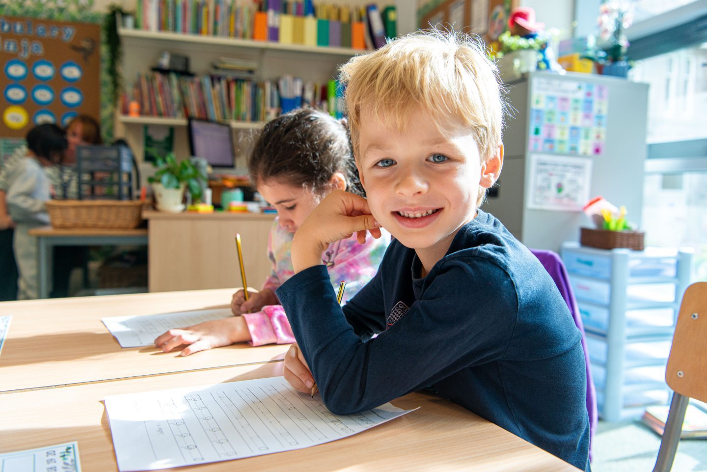 Smiling pupil at desk.