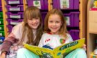 Two ISA students happily reading a book.