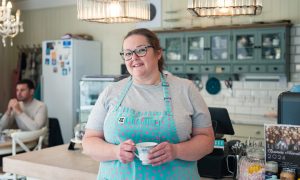 Laura Scott holding teacup standing at Ditsy Teacup counter.