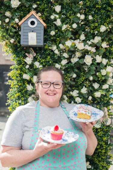 Laura Scott holding up cakes and scones. 