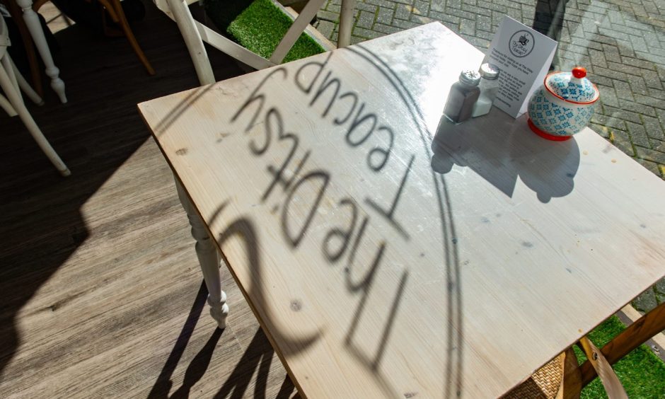 Silhouette of The Ditsy Teacup lettering on tables through window. 