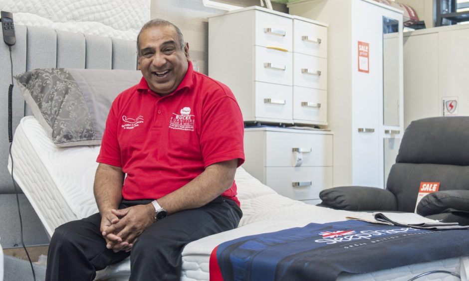 Zafar Ali laughing while sitting on bed. 