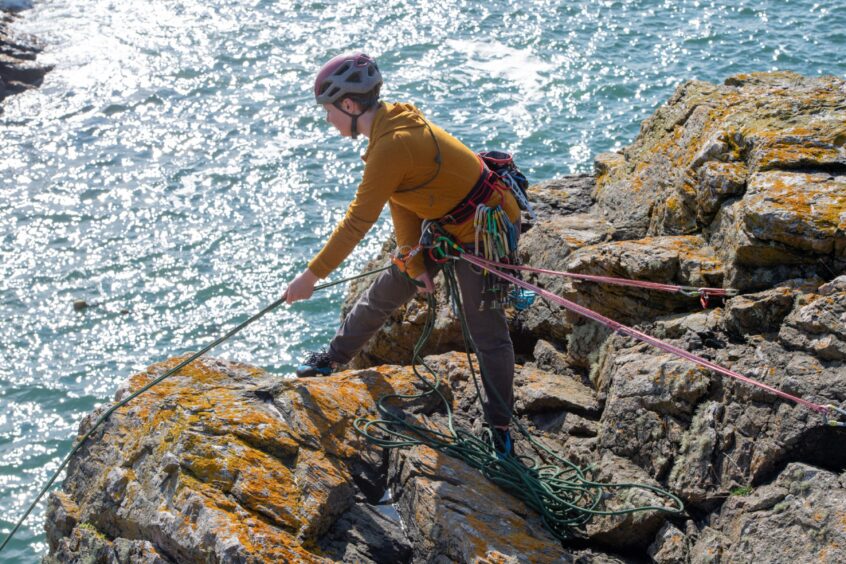 A Granite Girls climbing group member holding a climbing rope for the safety of another member