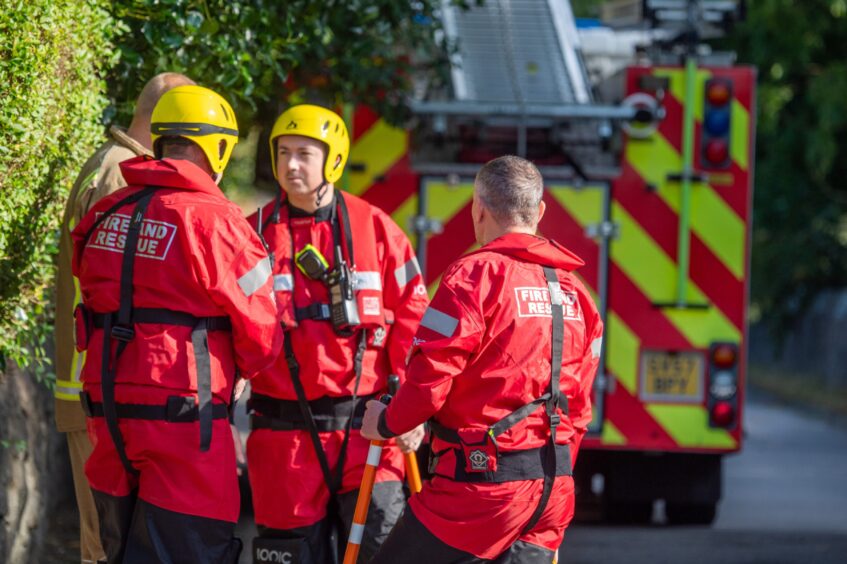 Members of the fire service's water resuce unilt dressed in red suits and yellow hard hats. 