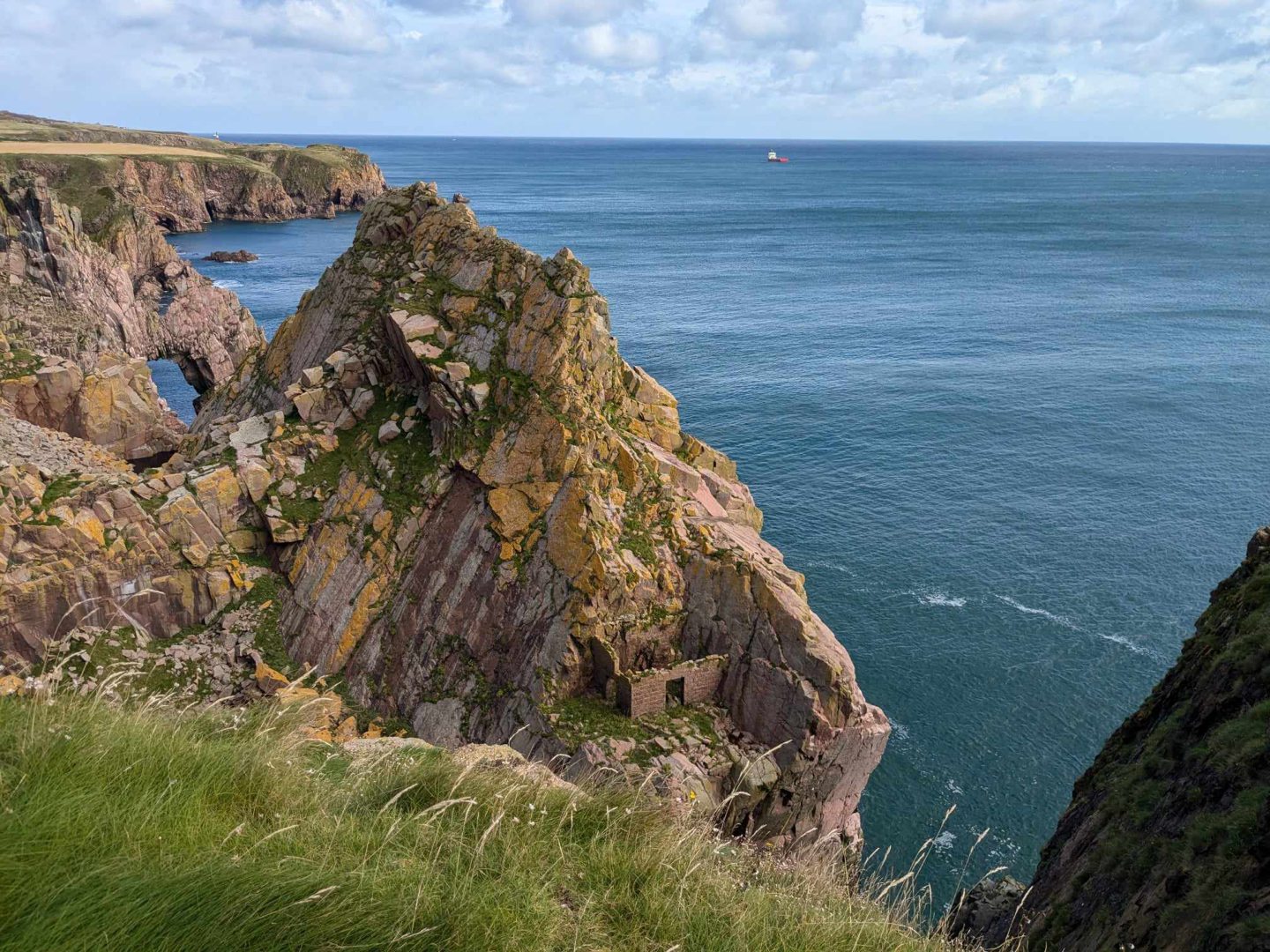 The ruined quarry bothy at Longhaven Cliffs, and an impressive sea arch in the background. Image: Gayle Ritchie.