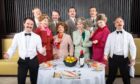 Cast of the Faulty Towers The Dining Experience standing behind a table.