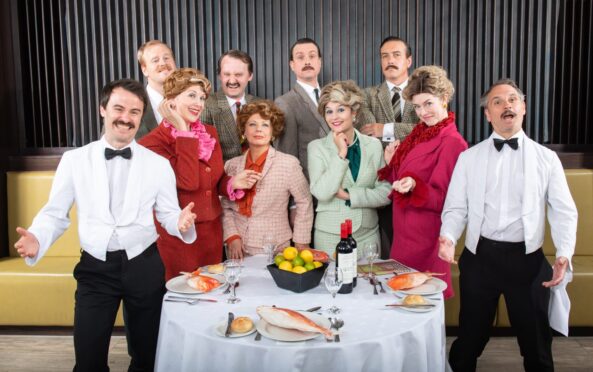 Cast of the Faulty Towers The Dining Experience standing behind a table.