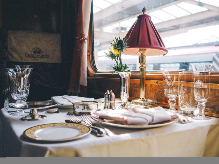 Dining table set with luxury crockery and a lamp onboard train.