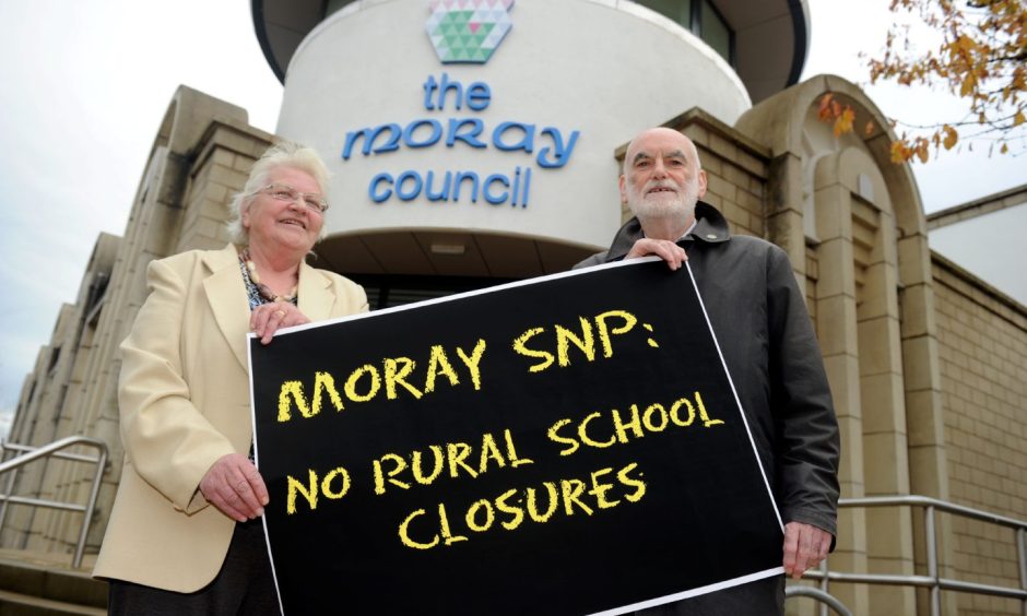 Councillors holding sign reading "Moray SNP: No rural school closures" outside Moray Council HQ