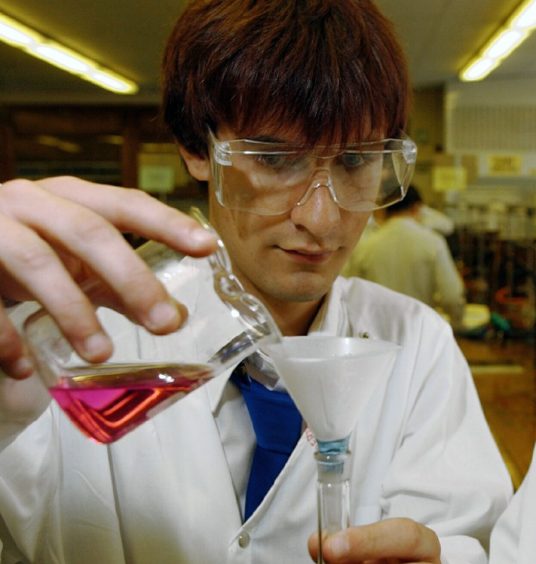 David Mackay holding chemistry equipment in lab. 