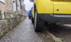 Yellow car parked on kerb.