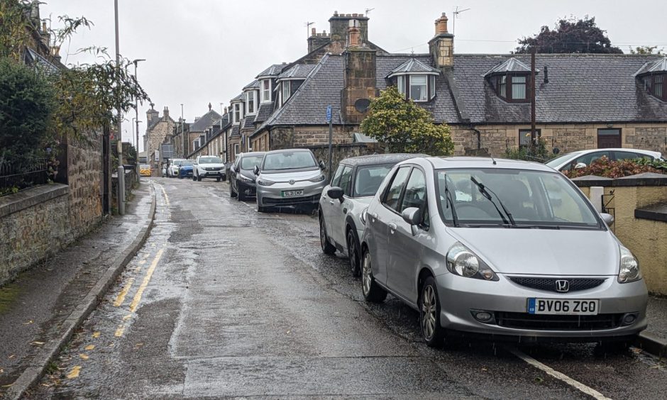 Looking up Academy Street with cars on pavement. 