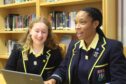 sitting in front of a laptop, rachel and yoma smile as they talk about being in an all girls school in Aberdeen