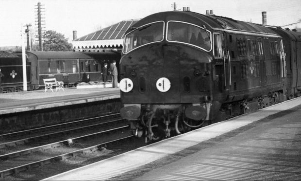 1961: A diesel creeps through Inverurie Station as the Duchess of Kent's steam powered train lies quietly in a siding. Image: DC Thomson