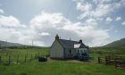 Bungalow surrounded by green fields and hills.