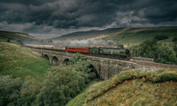 Northern Belle travelling across bridge with steam engine Tangmere hauling it through the countryside.