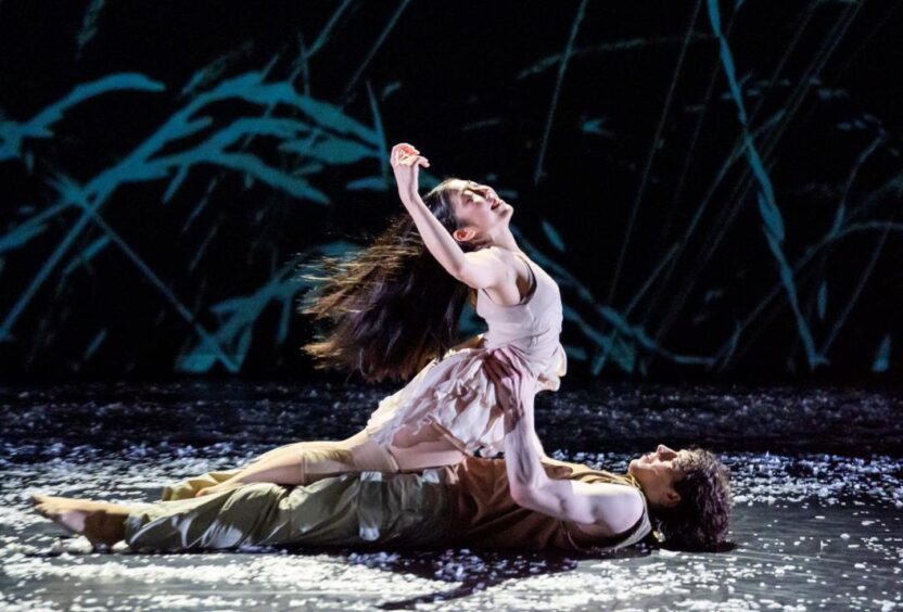 two dancers on a dark stage.