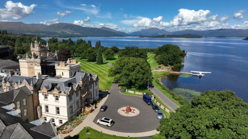 Aerial view of Cameron House Hotel with seaplane on water in background 