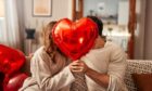 Couple holding a red balloon.