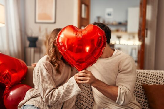 Couple holding a red balloon.