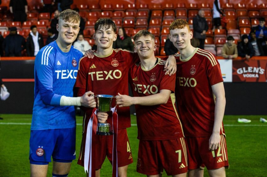 Smiling and holding the Club Academy Scotland League trophy at Pittodrie Stadium are Aberdeen's Rodrigo Vitols, Lewis Carrol, Cammy Wilson and Ellis Clark on May 13, 2024. Image: SNS.