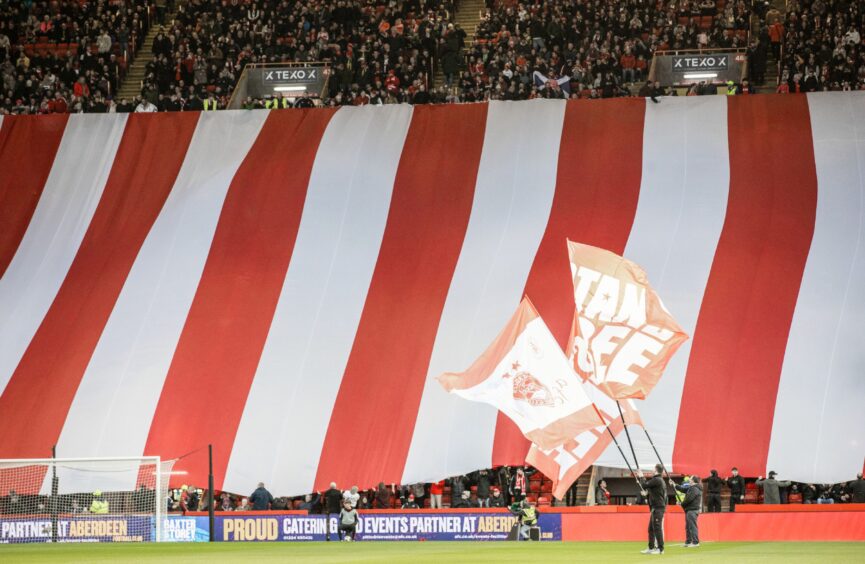 Aberdeen fans display flags and banners during a Premiership match against Dundee United at Pittodrie. Image: SNS